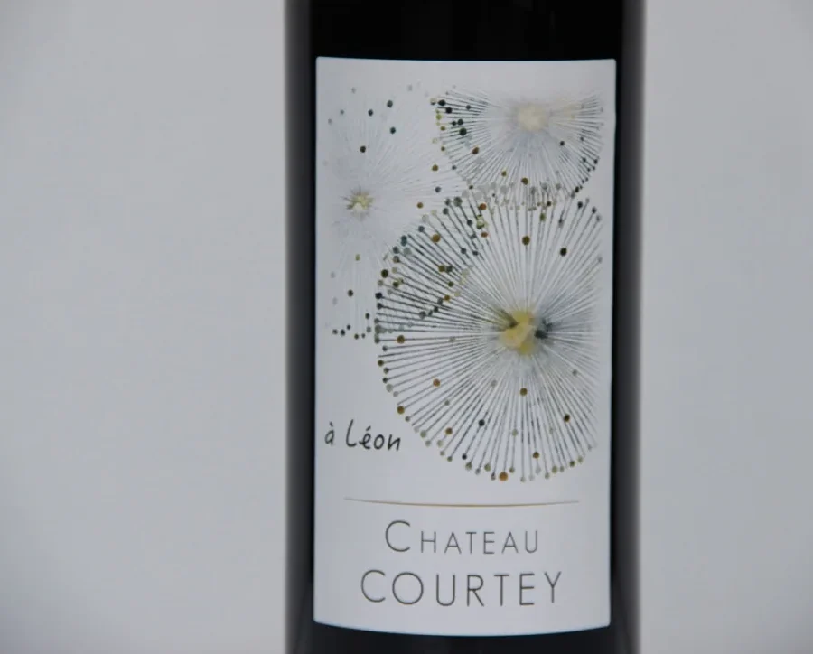 Une bouteille de Château Courtey, cuvée à Léon, son étiquette blanche aux ombelles dorées