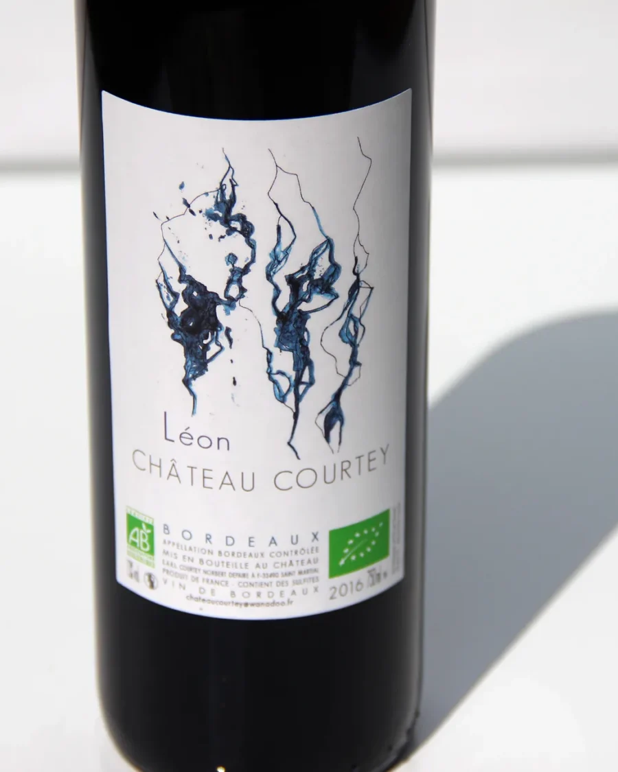 Une bouteille de Château Courtey, cuvée Léon, sur fond blanc, avec son ombre portée