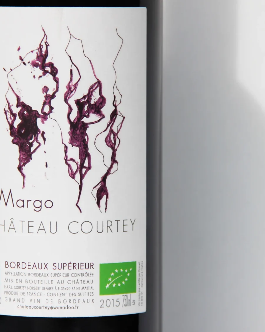 Une bouteille de Château Courtey, cuvée Margo, sur fond blanc, son étiquette marquée de traînées d'encre pourpre